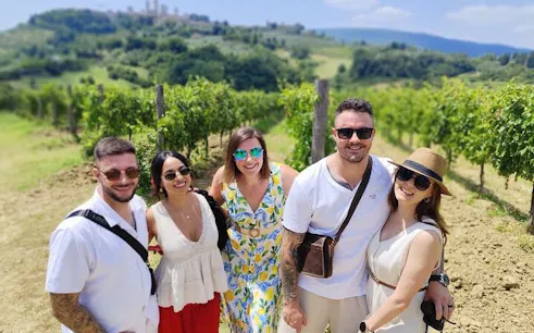 Tourists enjoying a vineyard in Tuscany with San Gimignano in the background.