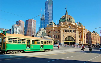 Flinders Street Station with a green tram in Melbourne, part of the Laneways and Arcades walking tour.