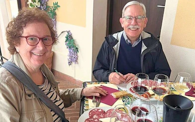 Couple enjoying wine tasting and charcuterie during Tuscan vineyard visit.
