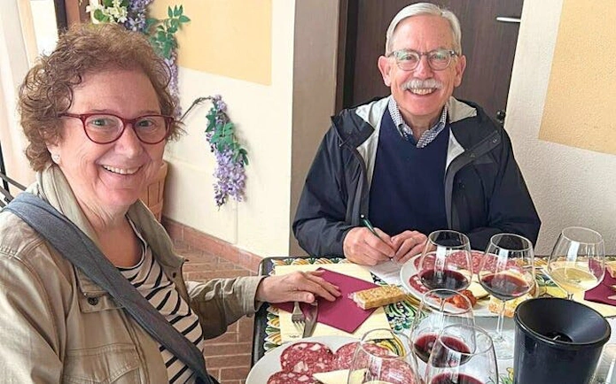 Couple enjoying wine tasting and charcuterie during Tuscan vineyard visit.