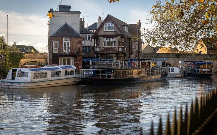 Boats docked along the river in Oxford with historic buildings in the background.