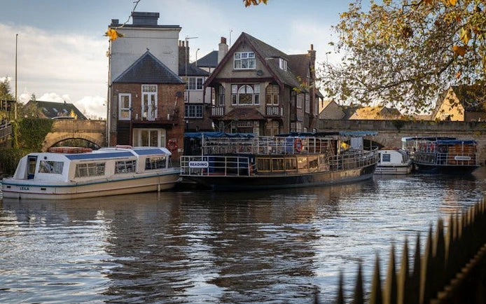 Boats docked along the river in Oxford with historic buildings in the background.