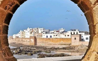 Essaouira cityscape viewed through a stone arch, featuring historic coastal walls and buildings.