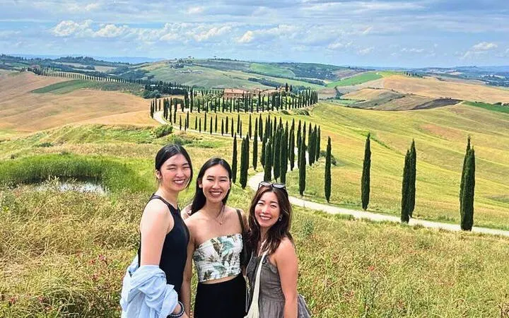 Tourists enjoying the scenic view of Val d'Orcia's rolling hills and cypress trees in Tuscany, Italy.