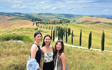 Tourists enjoying the scenic view of Val d'Orcia's rolling hills and cypress trees in Tuscany, Italy.