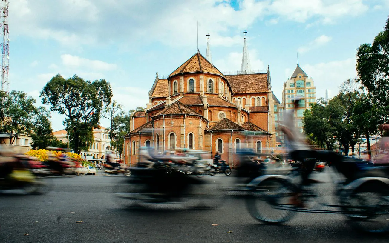 Notre-Dame Cathedral Basilica in Ho Chi Minh City with motorbikes passing by.
