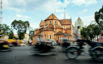 Notre-Dame Cathedral Basilica in Ho Chi Minh City with motorbikes passing by.