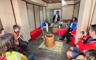 Participants in traditional attire engaging in mochi pounding experience in a Japanese setting.