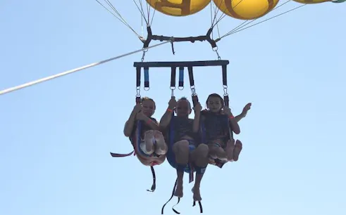 Parasailing over the Red Sea with three people in harnesses, Hurghada adventure.