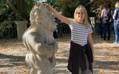 Girl touching a dwarf statue in Salzburg's Mirabell Gardens during a self-guided city exploration game.