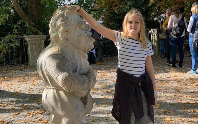 Girl touching a dwarf statue in Salzburg's Mirabell Gardens during a self-guided city exploration game.