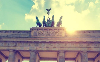 Brandenburg Gate in Berlin with sunlight behind, featured in self-guided walking tour app.