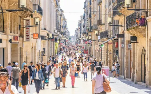 Crowded pedestrian street in Old Town Bordeaux with shops and historic architecture.