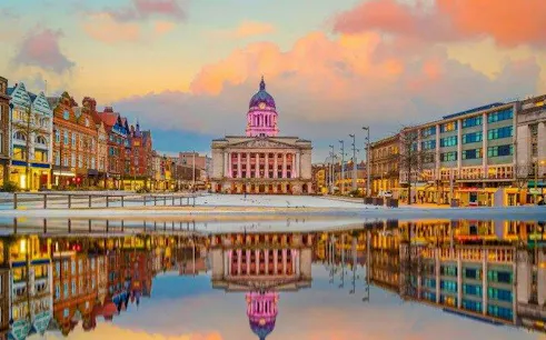 Nottingham Council House reflected in water at sunset, part of self-guided audio walking tour.