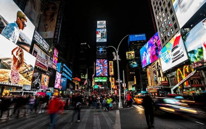 Times Square at night with bright billboards and crowds, part of New York self-guided walking tour.
