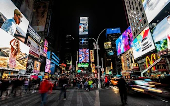 Times Square at night with bright billboards and crowds, part of New York self-guided walking tour.