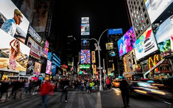 Times Square at night with bright billboards and crowds, part of New York self-guided walking tour.