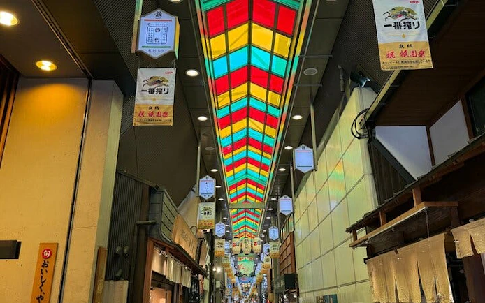 Nishiki Market in Kyoto with colorful ceiling and shops lining the walkway.