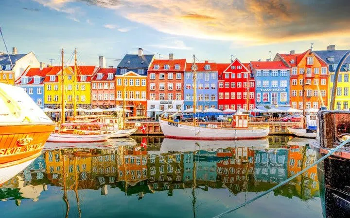 Colorful buildings and boats at Nyhavn Harbor, Copenhagen, featured in a self-guided walking tour app.