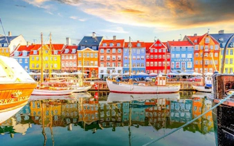 Colorful buildings and boats at Nyhavn Harbor, Copenhagen, featured in a self-guided walking tour app.
