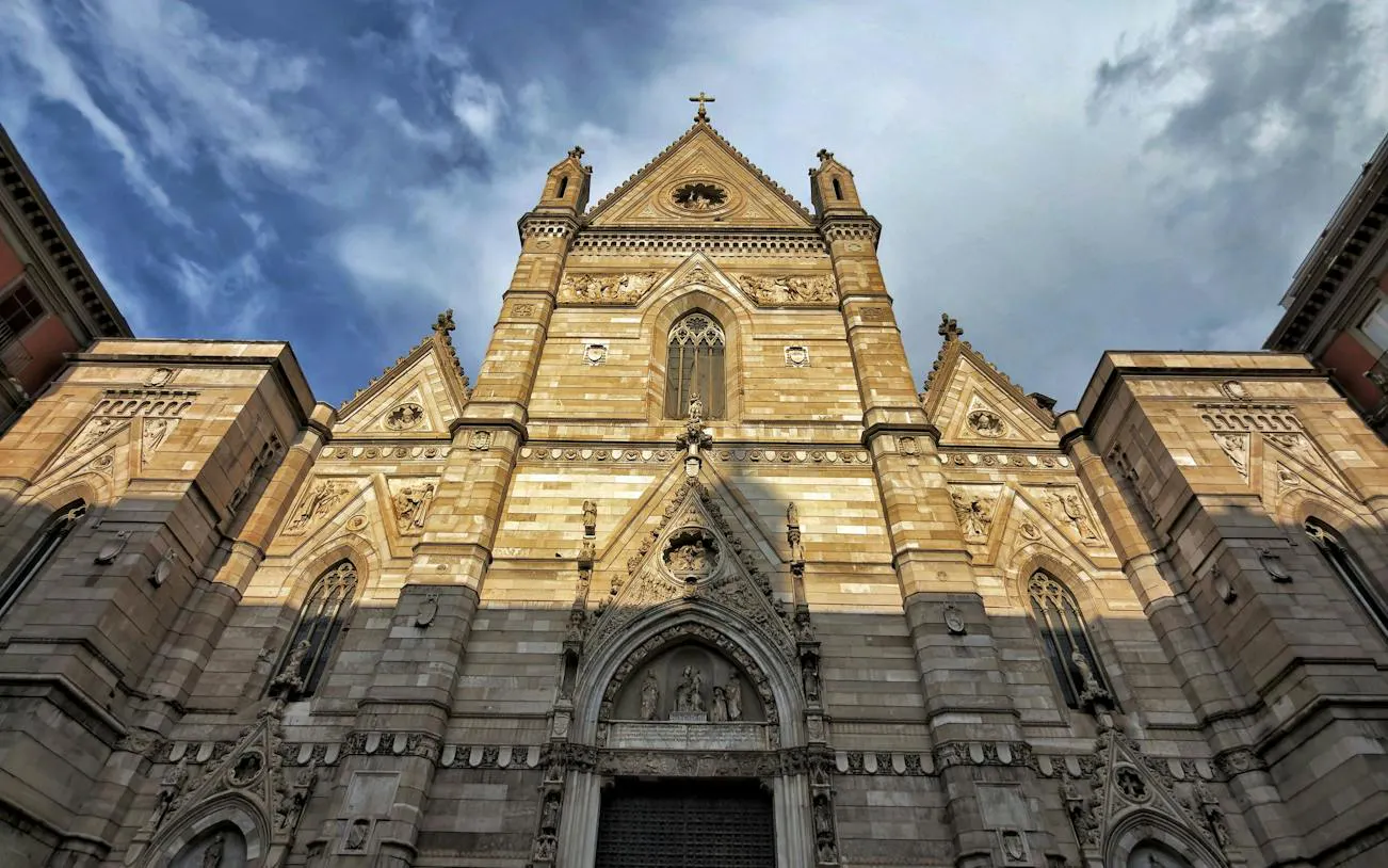 Naples Cathedral facade under a cloudy sky, part of the self-guided audio walk in Naples.