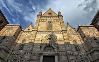 Naples Cathedral facade under a cloudy sky, part of the self-guided audio walk in Naples.