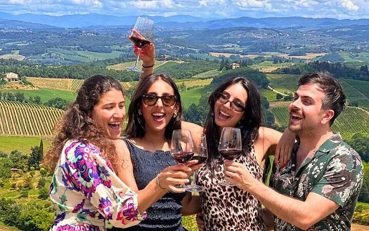 Group enjoying wine tasting with Tuscan vineyard view on day trip from Rome.