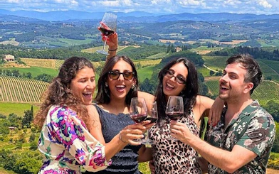 Group enjoying wine tasting with Tuscan vineyard view on day trip from Rome.