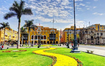 Plaza Mayor in Lima with colonial architecture and gardens on a sunny day.