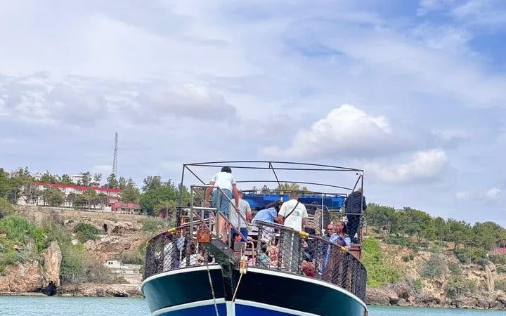 Boat approaching Antalya Lower Duden Waterfall with tourists on deck, Turkey.