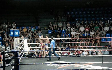 Muay Thai fighters in a match at Rajadamnern Stadium, Bangkok, with audience watching.