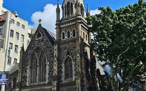 Historic stone church in Cape Town with gothic architecture, surrounded by city buildings and trees.