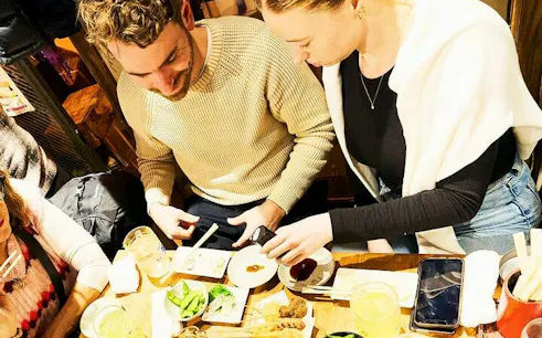 Dining at Shibuya eatery with skewers, edamame, and dipping sauces, Tokyo food tour.