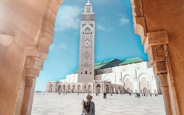 Hassan II Mosque in Casablanca viewed through an archway, with a visitor in the foreground.