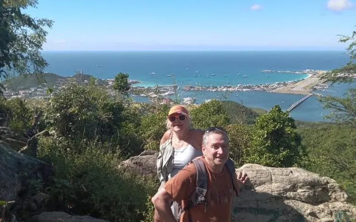 Hikers at Sint Maarten viewpoint overlooking ocean and town, experiencing nature and culture insights.
