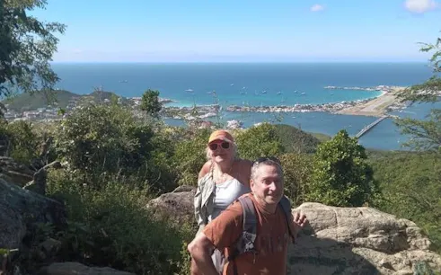 Hikers at Sint Maarten viewpoint overlooking ocean and town, experiencing nature and culture insights.