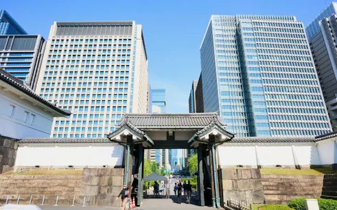 Tokyo Station gate with modern skyscrapers in the background, leading to Imperial Palace Outer Grounds.