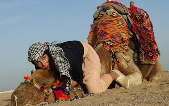 Person resting on a decorated camel in the Sharm El Sheikh desert.