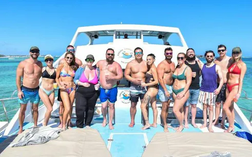 Group enjoying a party boat cruise in Punta Cana with clear blue water in the background.