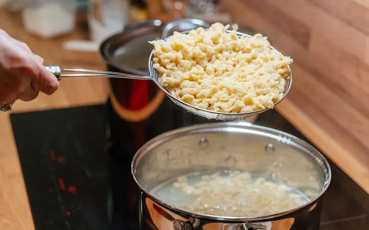 Cooking Hungarian dumplings in a pot during a Budapest family cooking class.
