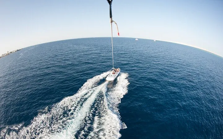 Parasailing over the Red Sea with a boat below, Hurghada adventure.