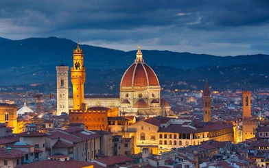 Florence skyline with illuminated Duomo and Palazzo Vecchio at dusk.