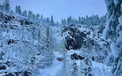 Korouoma frozen waterfalls surrounded by snow-covered trees in Rovaniemi.