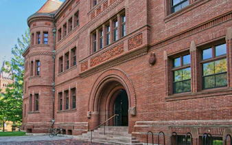 Harvard Yard brick building with arched entrance, part of self-guided audio walk in Boston.