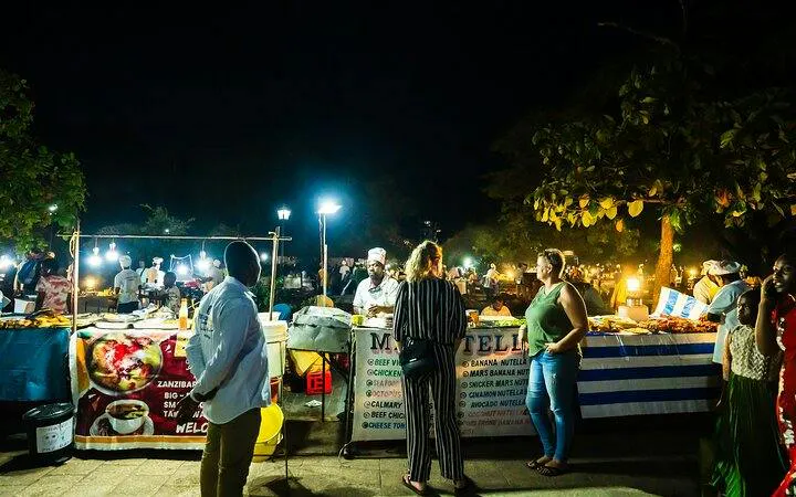 Stone Town Zanzibar night food market with people exploring food stalls.