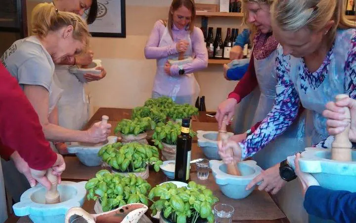 Participants making pesto in a cooking class with basil and olive oil in Manarola, Cinque Terre.