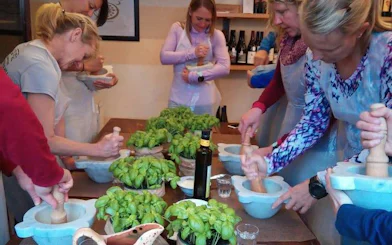 Participants making pesto in a cooking class with basil and olive oil in Manarola, Cinque Terre.