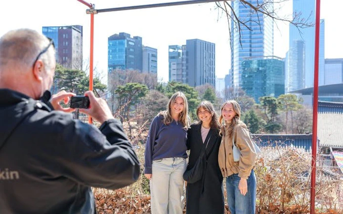Tourists posing for a photo with modern skyscrapers in Gangnam, Seoul, during a walking tour.