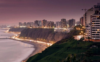 Lima coastline at dusk with city skyline and illuminated streets.