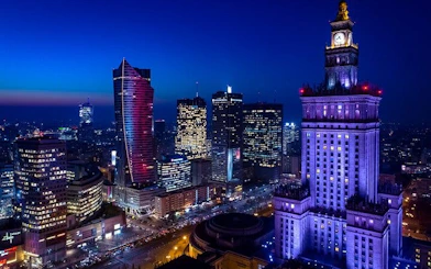 Warsaw skyline at night with illuminated Palace of Culture and Science.